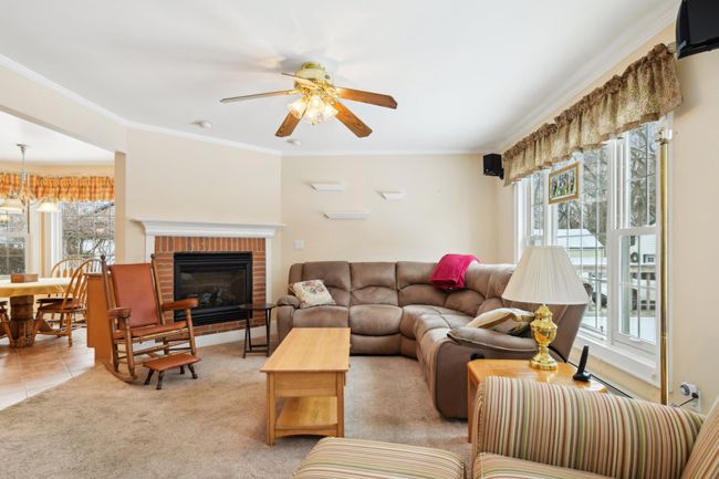 Tiled living room with crown molding, plenty of natural light, ceiling fan, and a fireplace | Image 12