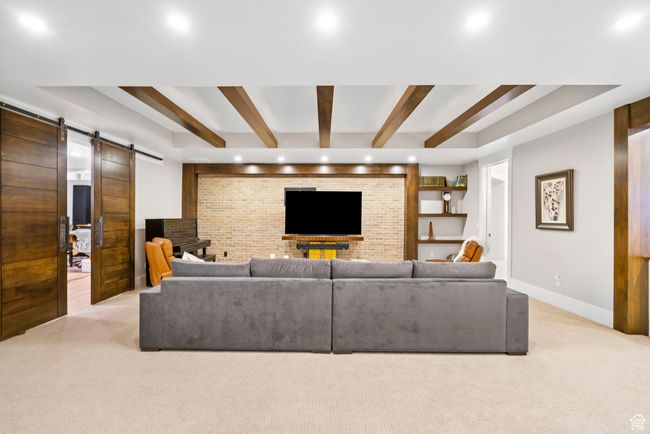 Living area with beamed ceiling, light colored carpet, recessed lighting, a barn door, and baseboards | Image 66