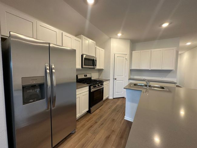 Kitchen with stainless steel appliances, wood finished floors, white cabinetry, and recessed lighting | Image 11
