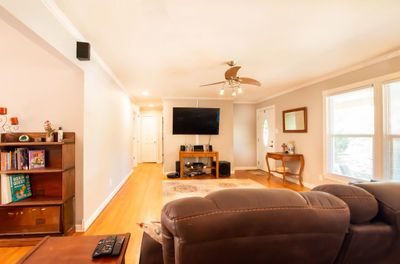 Living room with crown molding, light hardwood / wood-style flooring, and ceiling fan | Image 3