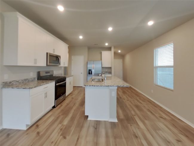 Kitchen featuring stainless steel appliances, white cabinets, light wood-style floors, light stone counters, and recessed lighting | Image 4