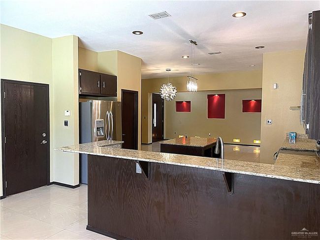 Kitchen with a center island, a kitchen breakfast bar, a peninsula, dark brown cabinetry, and recessed lighting | Image 5