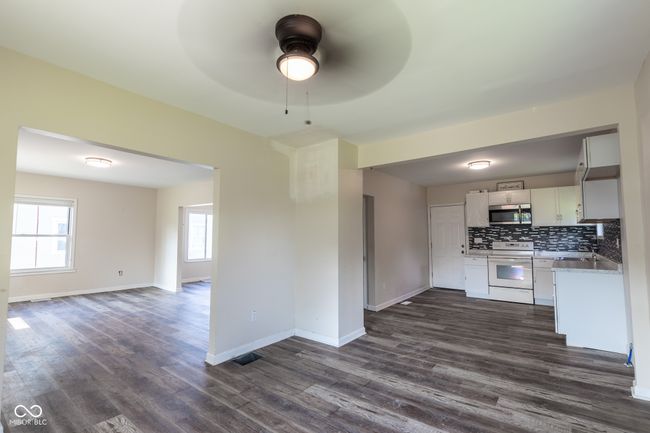 kitchen with white range with electric cooktop, open floor plan, ceiling fan, dark wood-style floors, and stainless steel microwave | Image 13