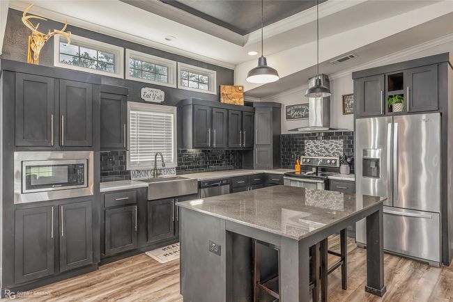 Kitchen with crown molding, light wood-style flooring, a sink, appliances with stainless steel finishes, and visible vents | Image 18