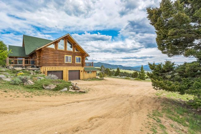 View of side of home featuring log exterior, dirt driveway, an attached garage, and a mountain view | Image 9