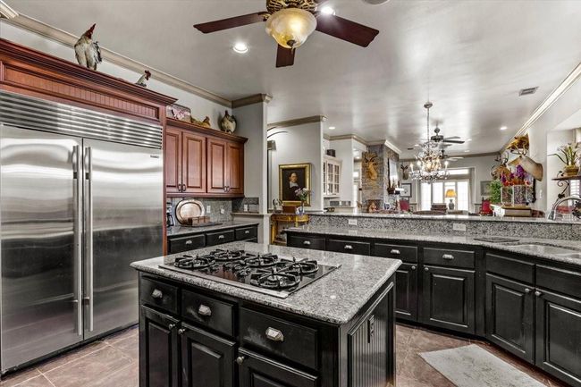 Ceiling fans throughout ensure that whatever room you are in is cool. Oversized built in refrigerator, cooktop island, and a kitchen bar that opens onto the dining area make entertaining a breeze. | Image 14