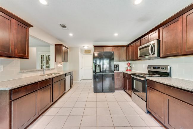 Kitchen featuring visible vents, a sink, stainless steel appliances, decorative backsplash, and light stone counters | Image 14