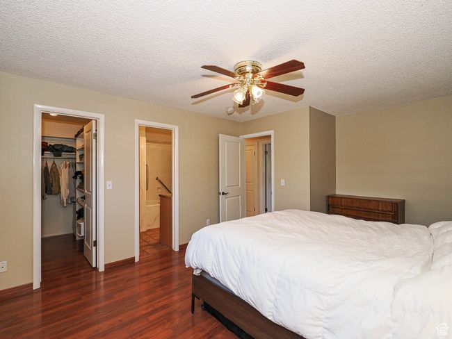 Bedroom featuring wood finished floors, a walk in closet, a closet, a textured ceiling, and ceiling fan | Image 20