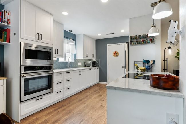 Kitchen featuring white cabinets, a sink, visible vents, backsplash, and appliances with stainless steel finishes | Image 9