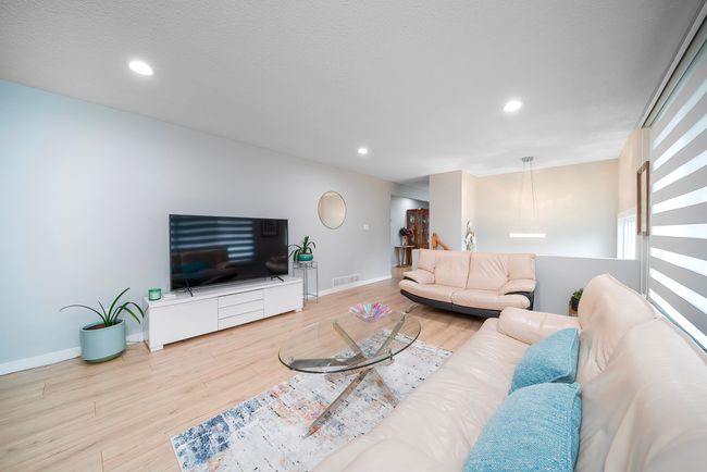 Living room with wood finished floors, a textured ceiling, baseboards, visible vents, and recessed lighting | Image 11
