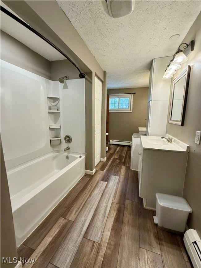 Full bathroom with shower / tub combination, a baseboard heating unit, baseboard heating, wood finished floors, and vanity | Image 26