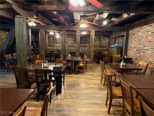 Dining area featuring a ceiling fan, wood finished floors, and brick wall | Image 31