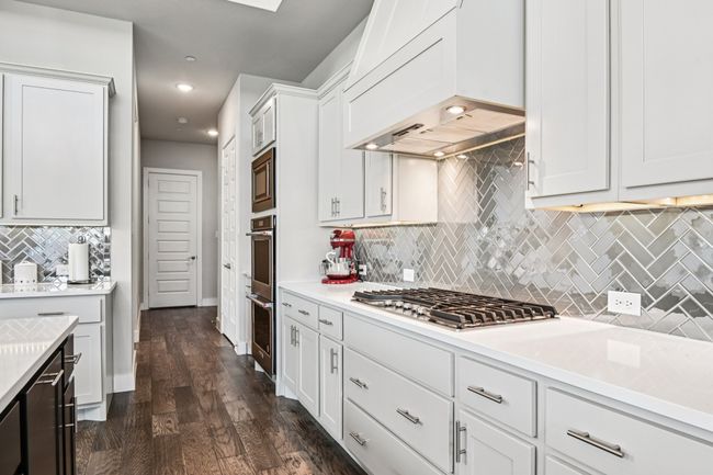 Kitchen with custom exhaust hood, appliances with stainless steel finishes, backsplash, light countertops, and recessed lighting | Image 13
