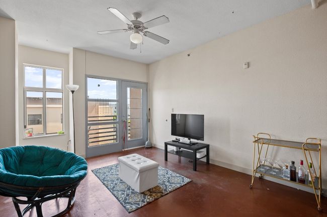 Living area with a ceiling fan, baseboards, and finished concrete flooring | Image 12