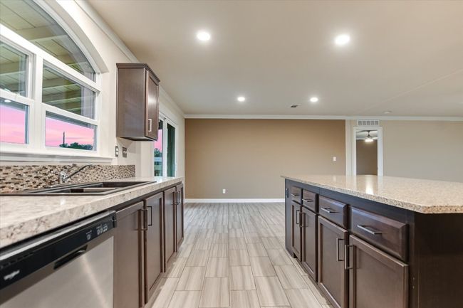 Kitchen with dishwasher, dark brown cabinets, a sink, ornamental molding, and recessed lighting | Image 11