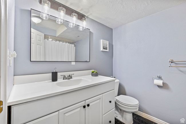 Bathroom featuring baseboards, a textured ceiling, vanity, and toilet | Image 31