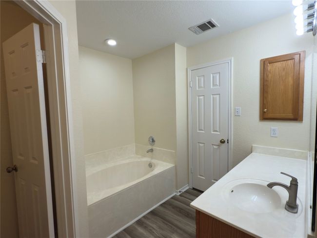 Full bathroom with wood finished floors, vanity, and a garden tub | Image 24