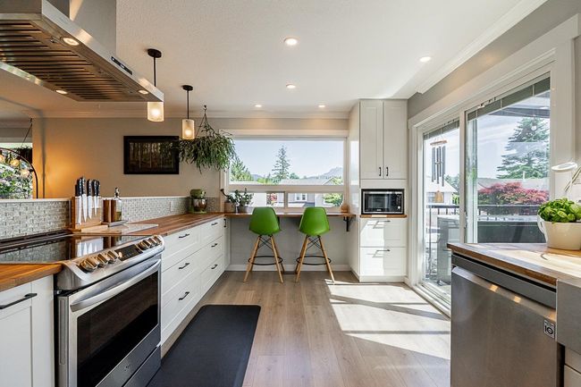 Kitchen with wood counters, wall chimney range hood, stainless steel appliances, healthy amount of natural light, and ornamental molding | Image 9
