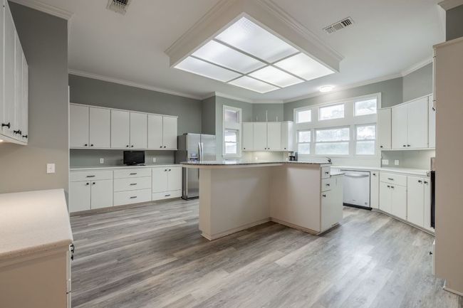 Kitchen with dishwasher, stainless steel fridge with ice dispenser, ornamental molding, a kitchen island, and light wood finished floors | Image 12