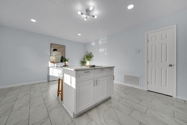 Kitchen with light marble finish flooring, white cabinetry, a kitchen island, recessed lighting, and light countertops | Image 30