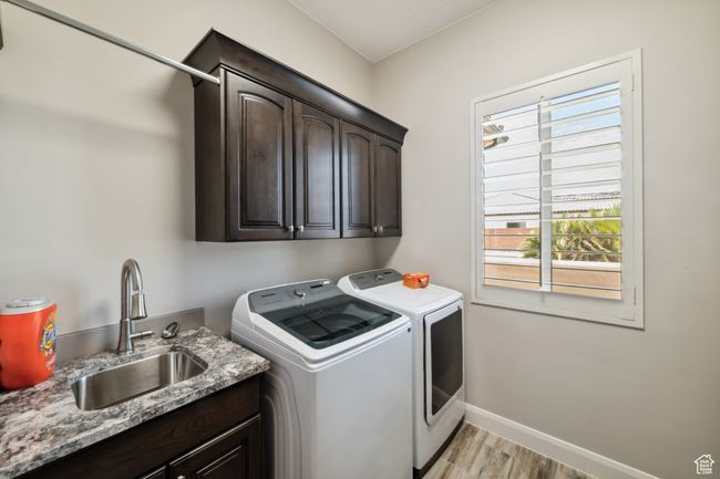 Washroom with washing machine and clothes dryer, a sink, baseboards, light wood-style floors, and cabinet space | Image 28