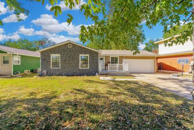 Ranch-style house featuring central air condition unit, a front lawn, and a garage | Image 1