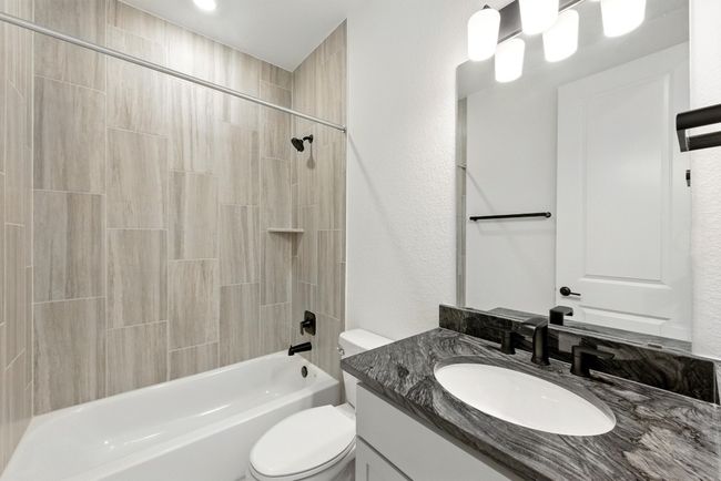 Bathroom featuring toilet, vanity, bathing tub / shower combination, and a textured wall | Image 29