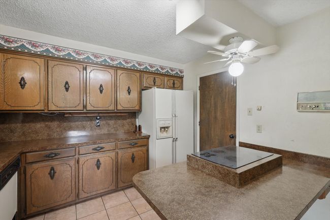 Kitchen with white appliances, brown cabinets, and dark countertops | Image 22