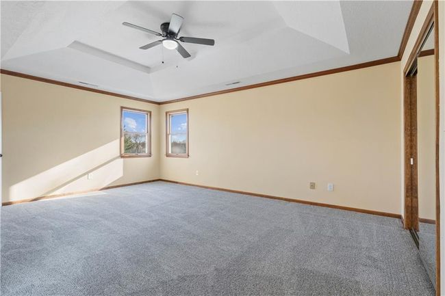 Unfurnished bedroom with a tray ceiling, crown molding, carpet flooring, and baseboards | Image 17