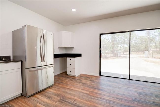 Kitchen featuring white cabinetry, freestanding refrigerator, baseboards, light wood-type flooring, and recessed lighting | Image 31