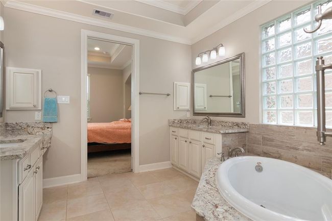 This bathroom features a spacious layout with a large bathtub, dual sinks with granite countertops, and ample cabinet storage. | Image 32