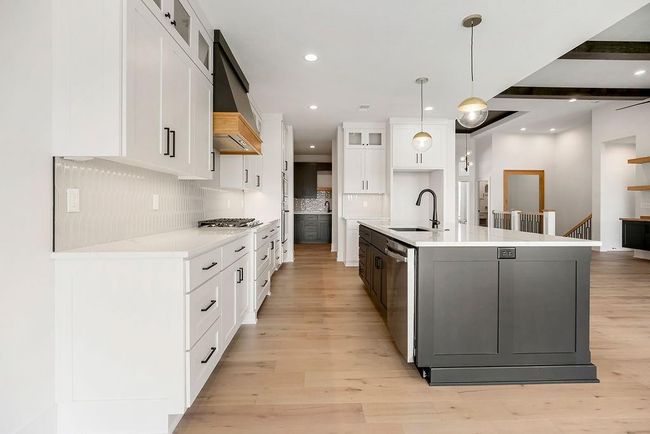 Kitchen featuring a sink, appliances with stainless steel finishes, backsplash, a kitchen island with sink, and glass insert cabinets | Image 10