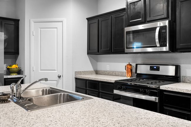 Kitchen featuring light countertops, a sink, stainless steel appliances, and dark cabinets | Image 8