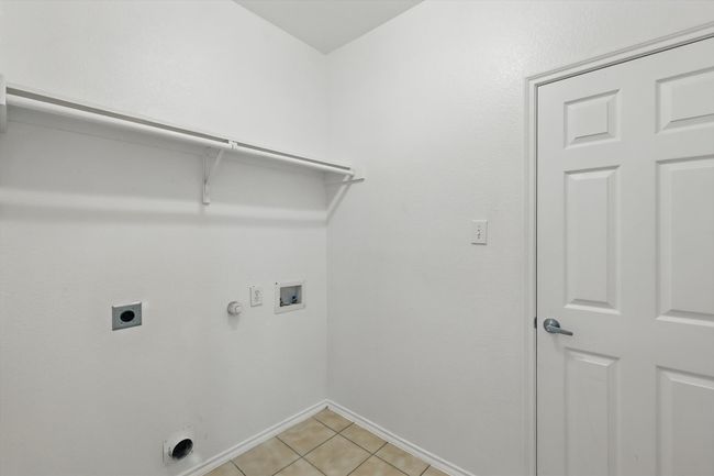 Washroom with electric dryer hookup, hookup for a washing machine, gas dryer hookup, and light tile patterned flooring | Image 16