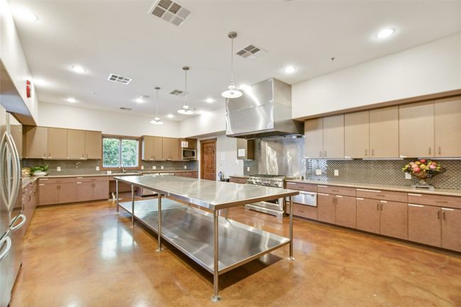 Clubhouse Kitchen with decorative backsplash, hanging light fixtures, finished concrete flooring, range hood, and recessed lighting | Image 33
