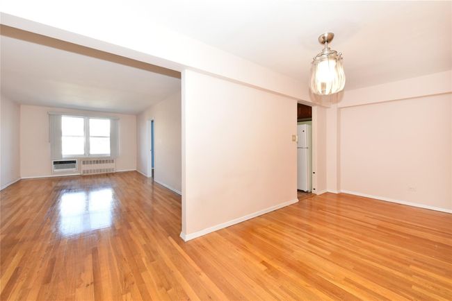 Empty room featuring radiator heating unit, a wall mounted air conditioner, and light wood-type flooring | Image 13
