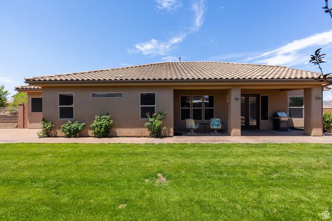 Rear view of property with a tiled roof, stucco siding, a yard, and a patio area | Image 9