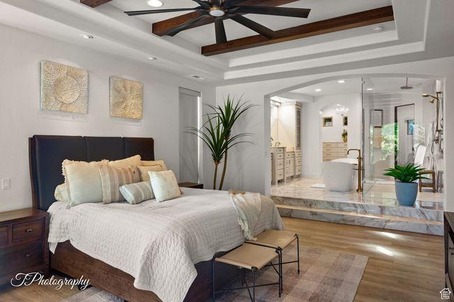 Bedroom featuring a raised ceiling, arched walkways, wood finished floors, recessed lighting, and ensuite bathroom | Image 27