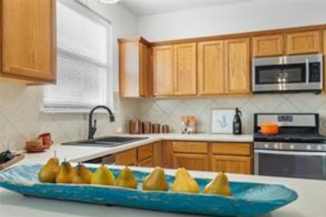 Kitchen with brown cabinets, decorative backsplash, a sink, appliances with stainless steel finishes, and light countertops | Image 12