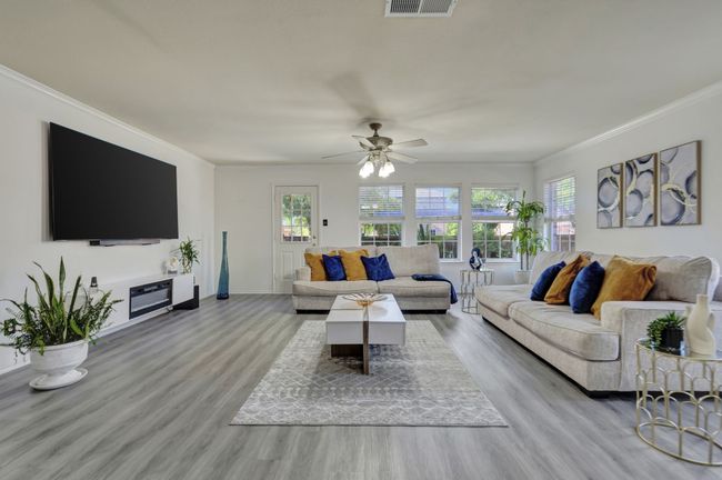 Living room featuring ceiling fan, light wood-type flooring, crown molding, and a healthy amount of sunlight | Image 17