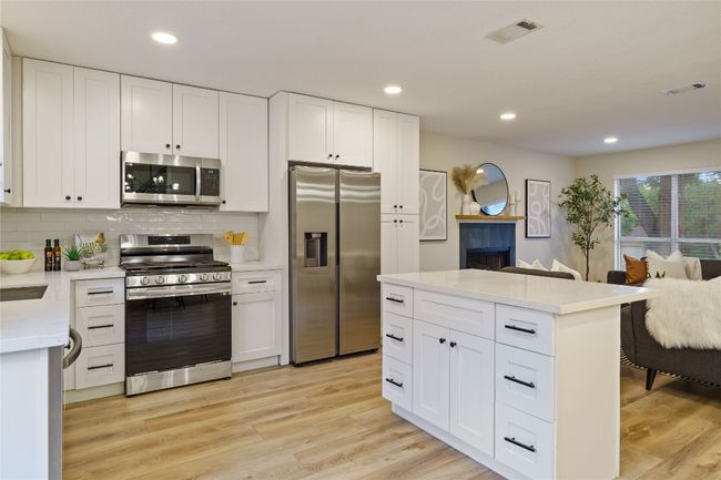 Kitchen featuring tasteful backsplash, stainless steel appliances, light countertops, light wood finished floors, and visible vents | Image 11