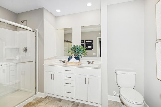(Photo of model home, features will vary) Featuring a glass-enclosed shower with built-in shelving and glass mirrors set atop dual quartz sinks and vanity-cabinetry, the en-suite bathroom helps streamline morning routines | Image 11