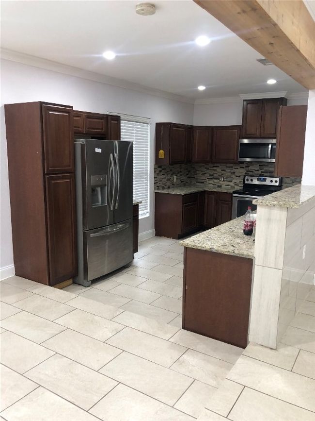 Kitchen with appliances with stainless steel finishes, backsplash, dark brown cabinetry, ornamental molding, and recessed lighting | Image 8