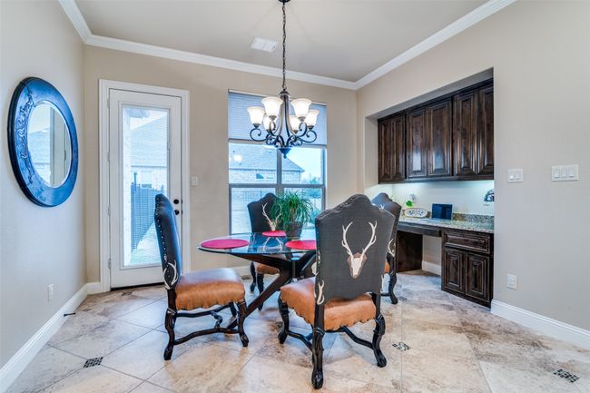 Dining space featuring ornamental molding, baseboards, a chandelier, and built in study area | Image 18