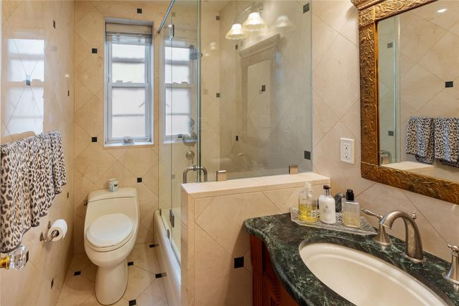 Bathroom with tile walls, vanity, tile patterned floors, and shower / bath combination with glass door | Image 19