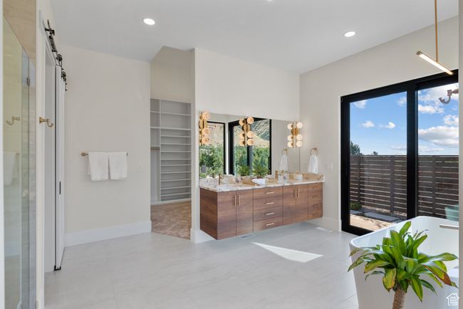 Bathroom featuring double vanity, a shower stall, a soaking tub, a spacious closet, and recessed lighting | Image 42