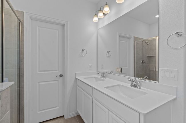 Full bathroom featuring double vanity, tiled shower, and tile patterned floors | Image 24
