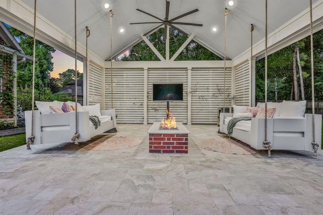 Form meets function in the most elegant way beneath the gable pergola. This beautifully crafted structure features a gabled ceiling accented by an extra-large ceiling fan and a natural gas fire pit. Two inviting bed swings, on either side, frame the area —ideal for afternoon naps, reading, or enjoying friends and family. | Image 4