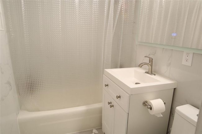 Full bathroom featuring shower / bath combination with curtain, toilet, and vanity with extensive cabinet space | Image 12