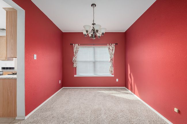 Empty room with a chandelier, light colored carpet, and a textured wall | Image 6